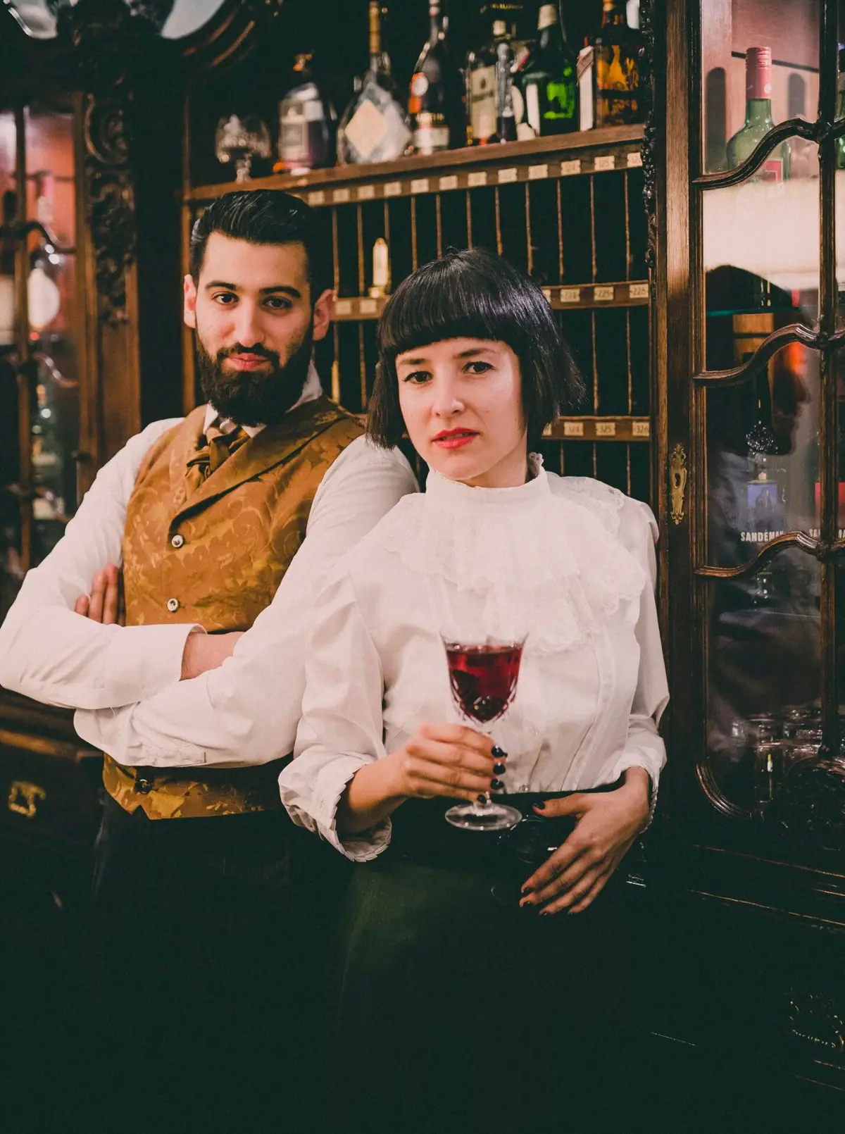 A man and a woman pose for a photo, both holding a drink.