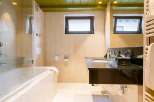 Bathroom with washbasin and bath, fitted with taps and a mirror.