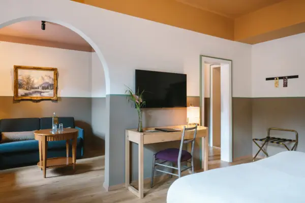 A spacious hotel room at the HENRI Hotel in Garmisch-Partenkirchen, with a walk-through from the bedroom to the living area.