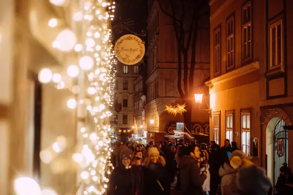 Crowd of people on a street with Christmas lights.