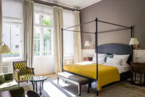 A room featuring a neatly made bed with pillows and a nearby chair.