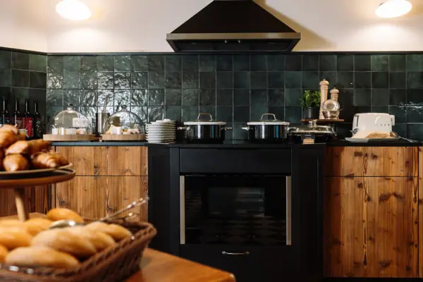 A kitchen with black appliances and a basket of bread on the countertop.