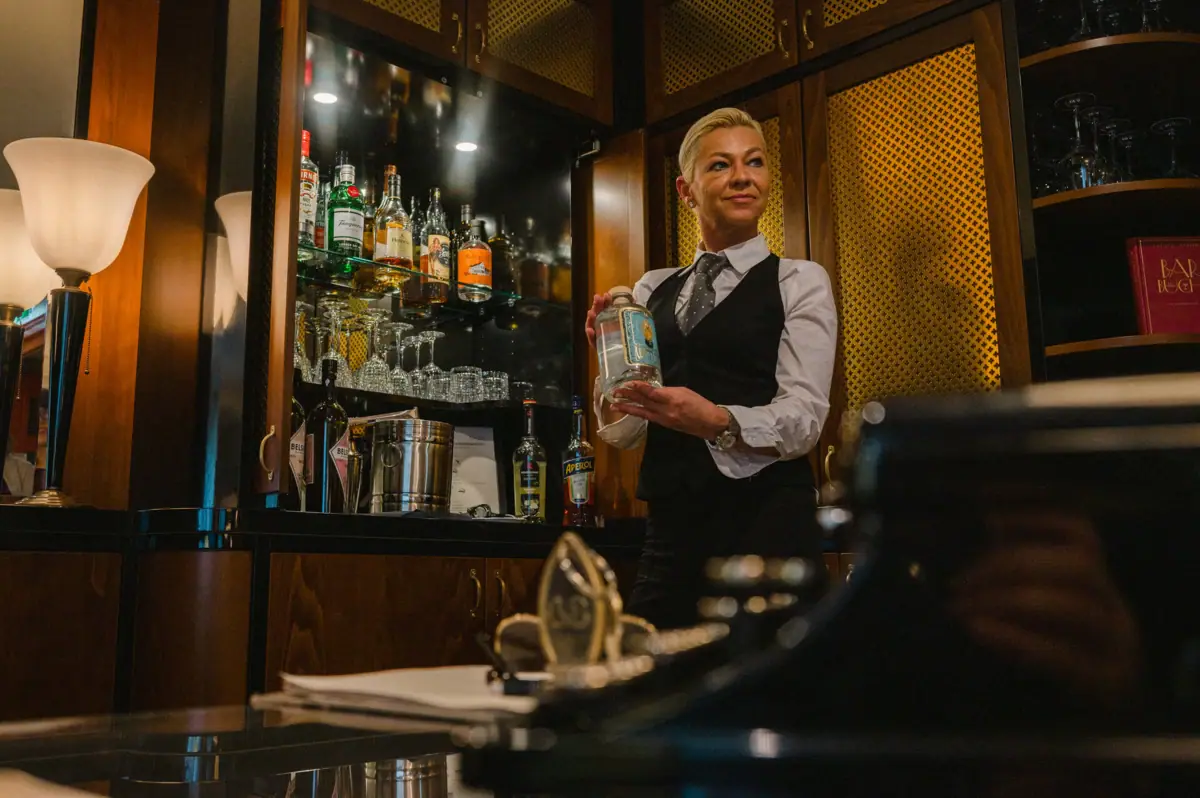 A woman holds a bottle of alcohol.