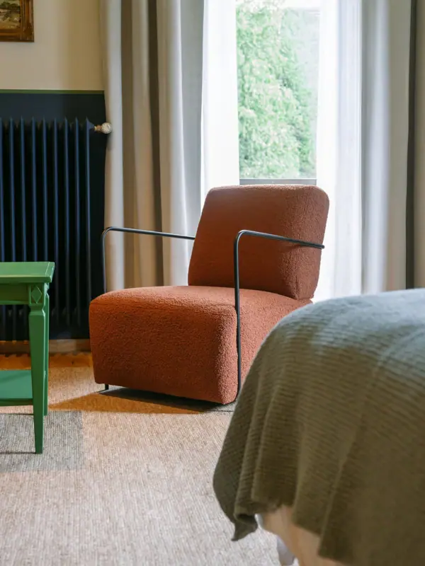 A chair in a well-designed room with a pillow on it.