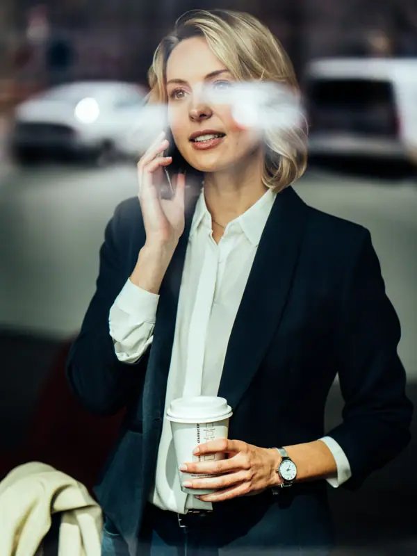 A woman is holding a coffee mug and talking on the phone.