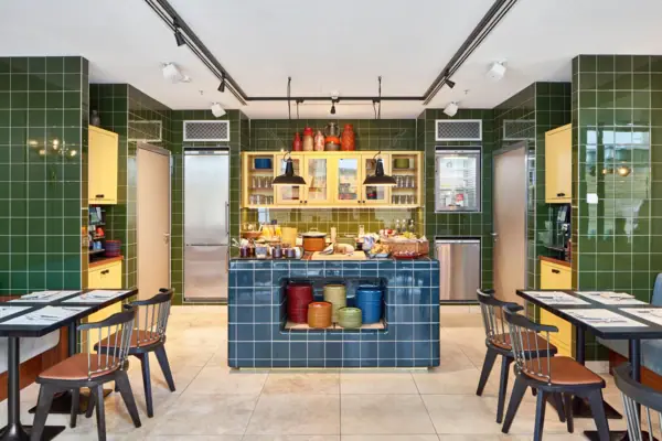 HENRI Düsseldorf A kitchen with green tiles, a blue tiled worktop and chairs.