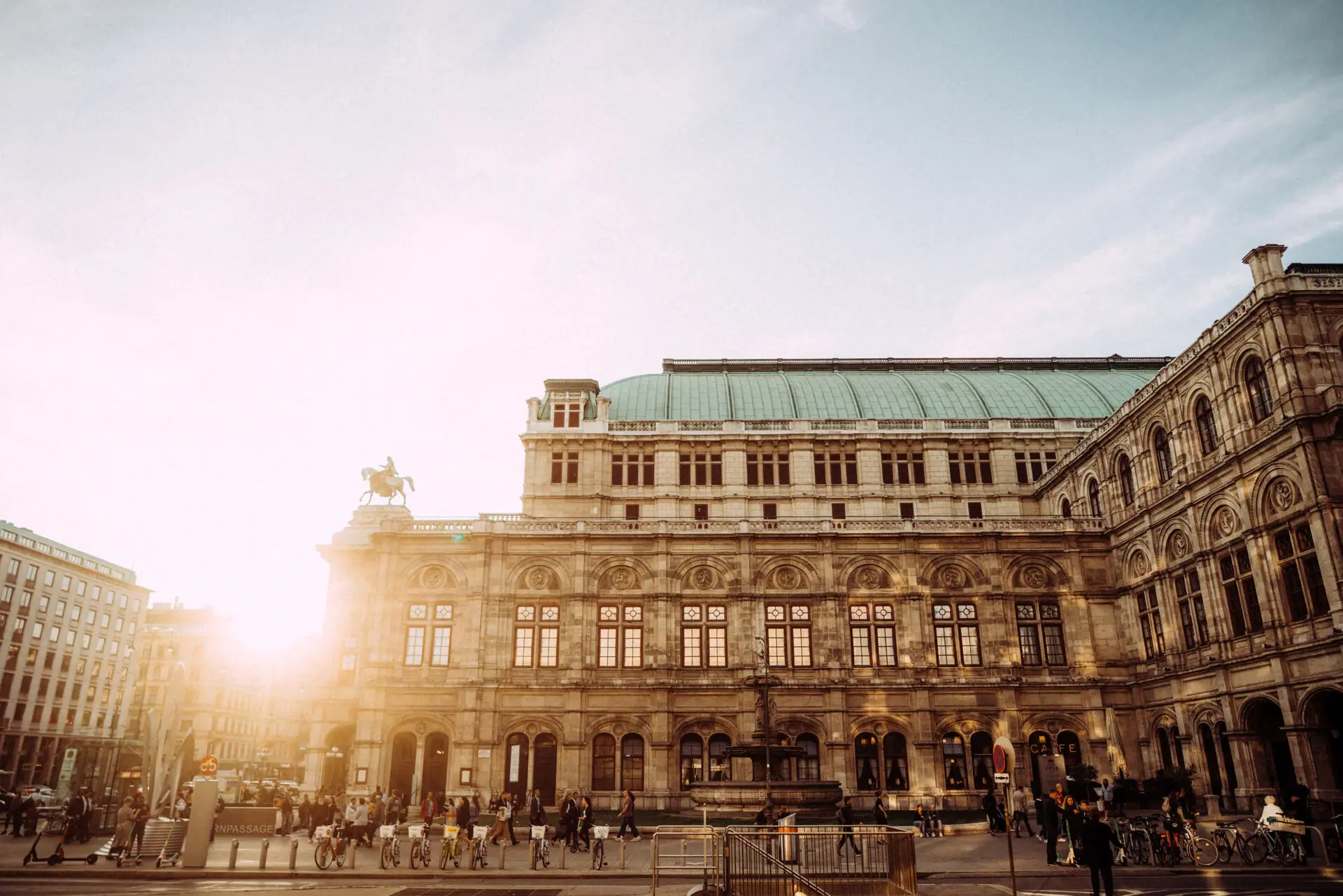 A large building with people walking along the pavement.