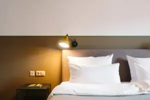 A bed with white pillows and a lamp at the HENRI Hotel Garmisch-Partenkirchen.