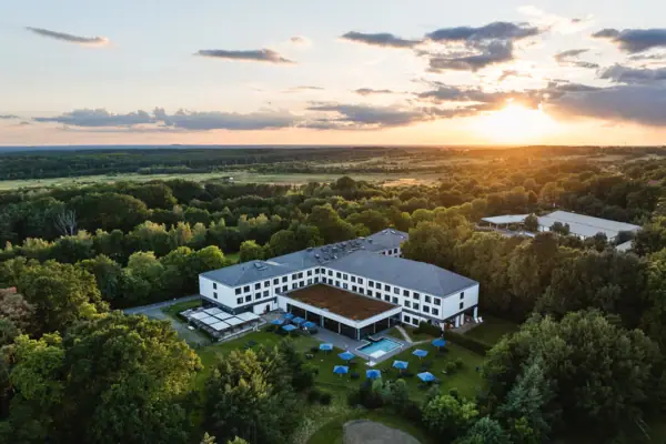The aja Hotel in Bad Saarow with a pool surrounded by trees.
