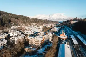 HENRI Kitzbühel: aerial view A snow-covered town in winter, with mountains in the background.