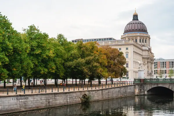 A building with a dome and trees by a river.