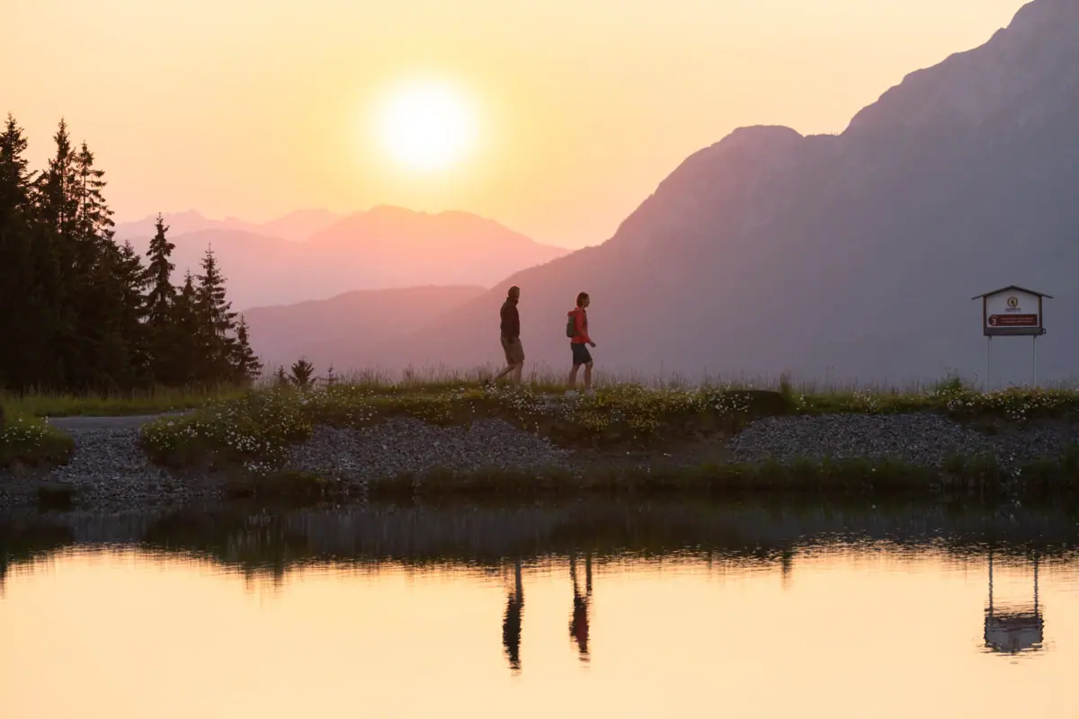 Two people are walking on a hill by a lake.