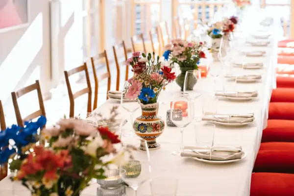 A long table with a floral arrangement and wine glasses.