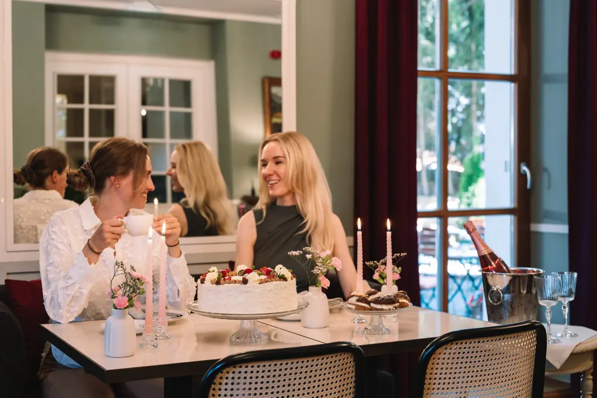 Two women are sitting at a table with a cake and candles.