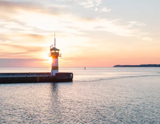 A lighthouse in Travemünde on a jetty in the middle of the ocean.