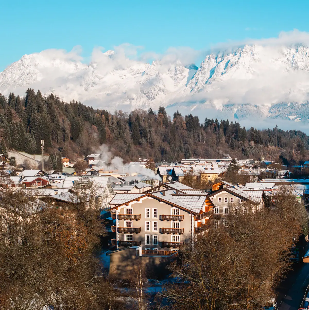 The town of Kitzbühel in winter with snow-covered mountains in the background.
