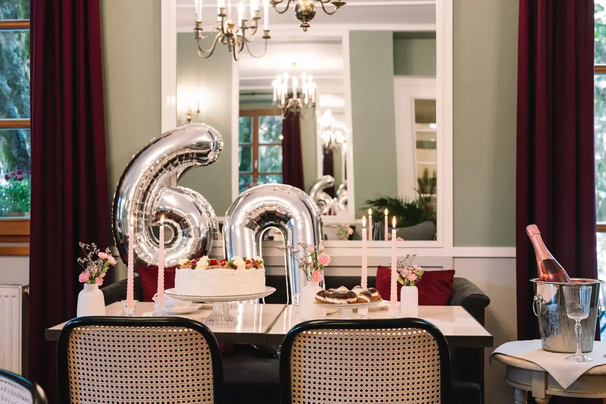A table with a cake and some balloons on it.