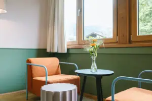 A table and a chair in a cosy hotel room at the HENRI Hotel Garmisch-Partenkirchen.