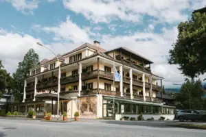 Exterior view of the HENRI Hotel in Garmisch-Partenkirchen, with trees and a road.