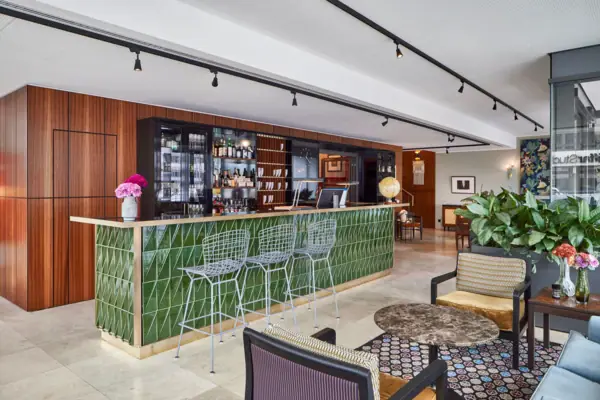 A bar with green tiles and chairs.