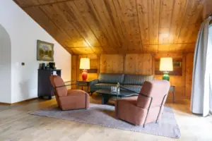 A room with a sofa and chairs.