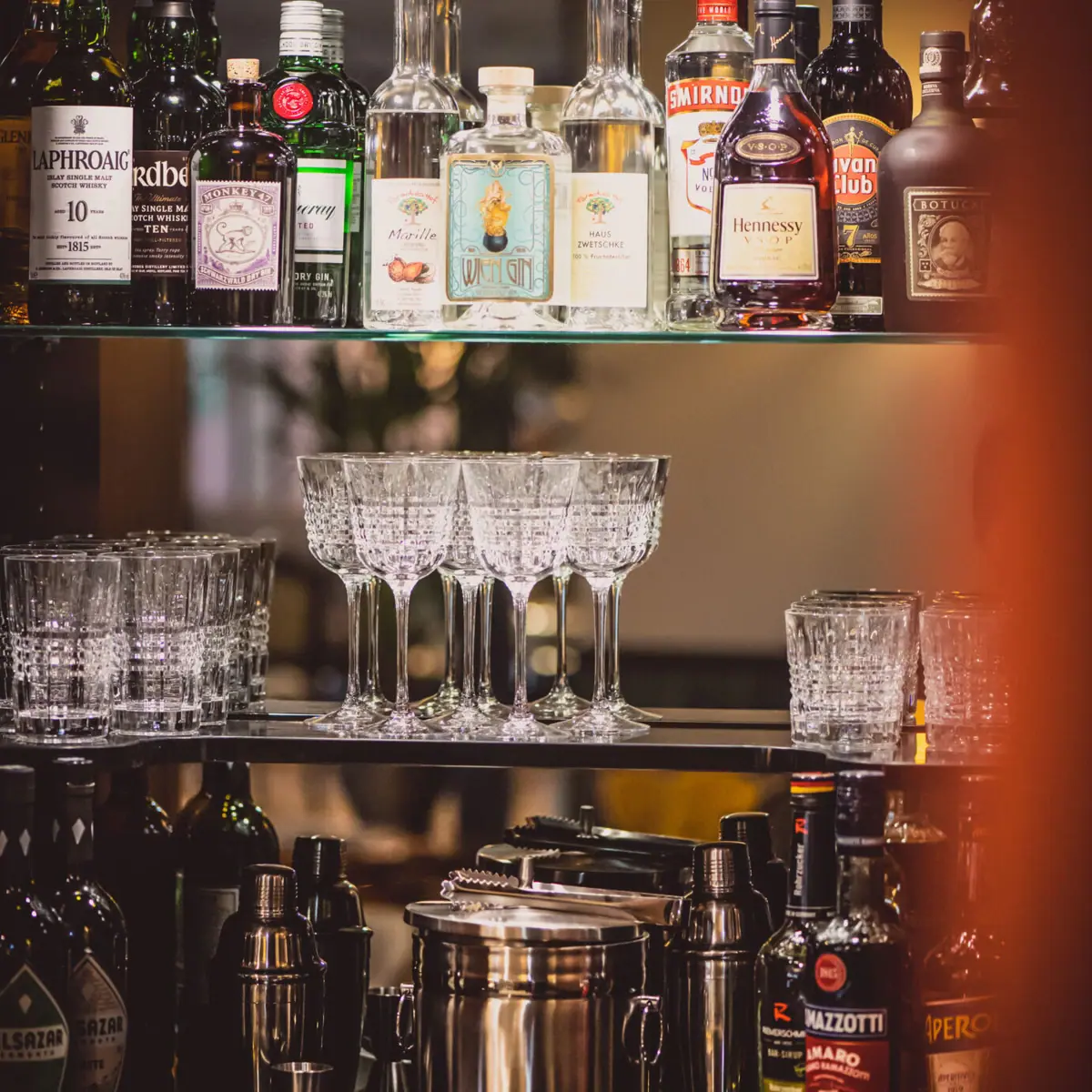 Shelf with glasses and bottles of alcoholic drinks in a bar.