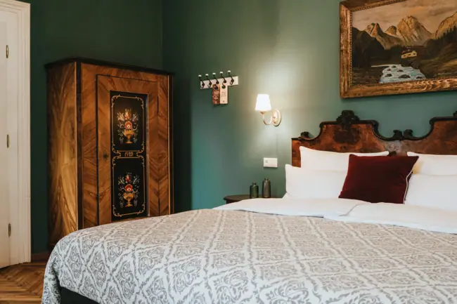 Rooms at the HENRI Hotel Kitzbühel A bed with pillows and a wardrobe in a room.
