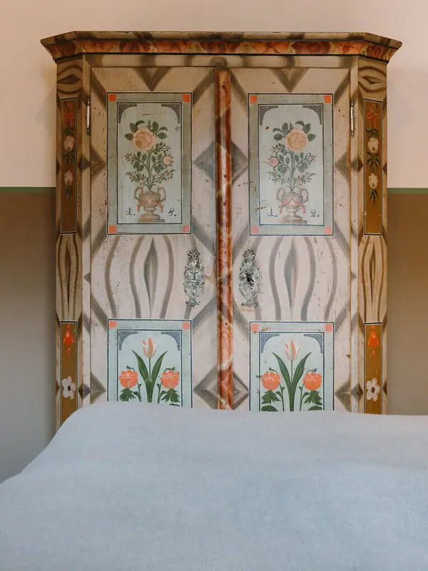 A bed with a painted wardrobe in the background.