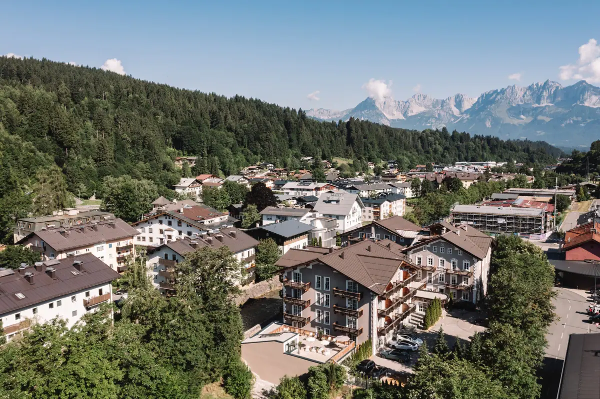 HENRI Hotel Kitzbühel A group of buildings with trees and mountains in the background.