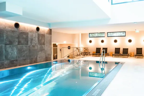 An indoor pool with steps and chairs.