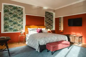 The Salon hotel room at the HENRI Hotel Kitzbühel with red walls and a large bed.