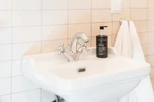 Mirror above a washbasin with a flower in a vase