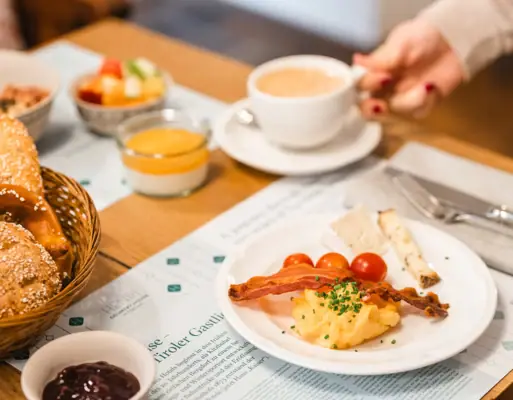 One person is holding a cup of coffee and a plate of food.