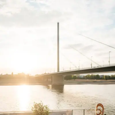 A group of people are sitting on chairs on the riverbank.