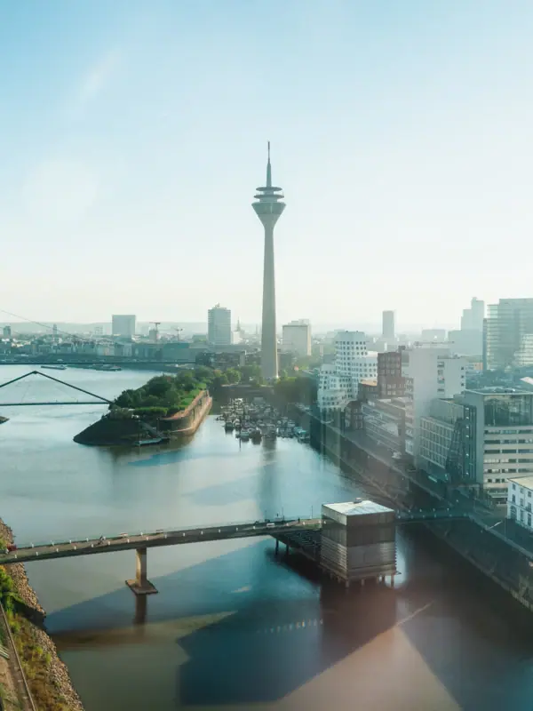 A river with a bridge and a town with a tower.
