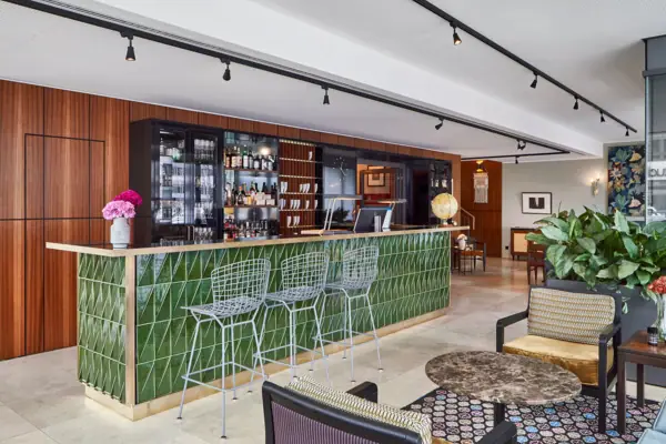 A bar with green tiles and chairs.