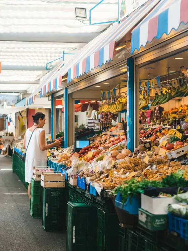 Woman standing in front of a fruit stall at a market.
