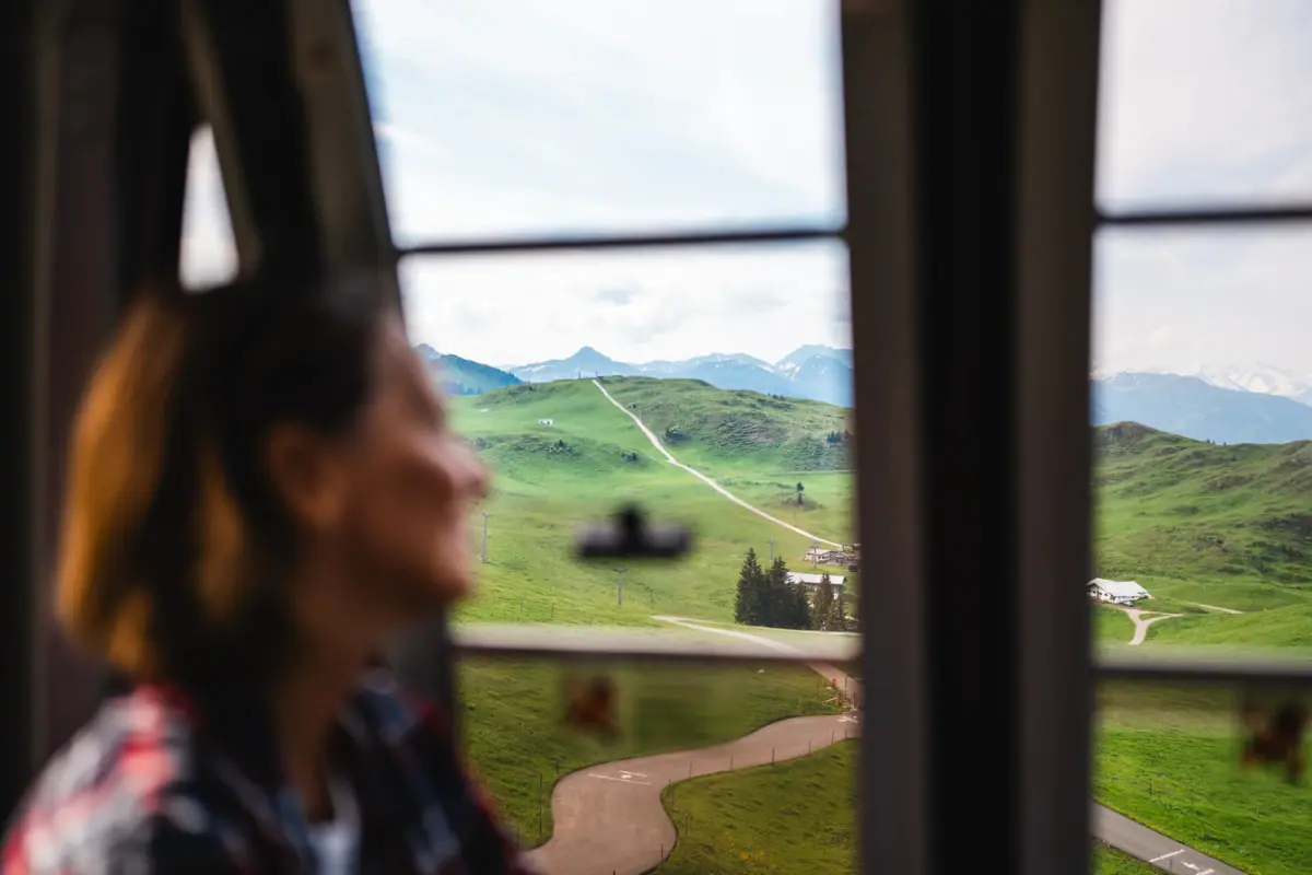 A woman looks out of a window at a landscape.