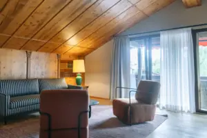 A room with a wooden ceiling, a sofa and armchairs.