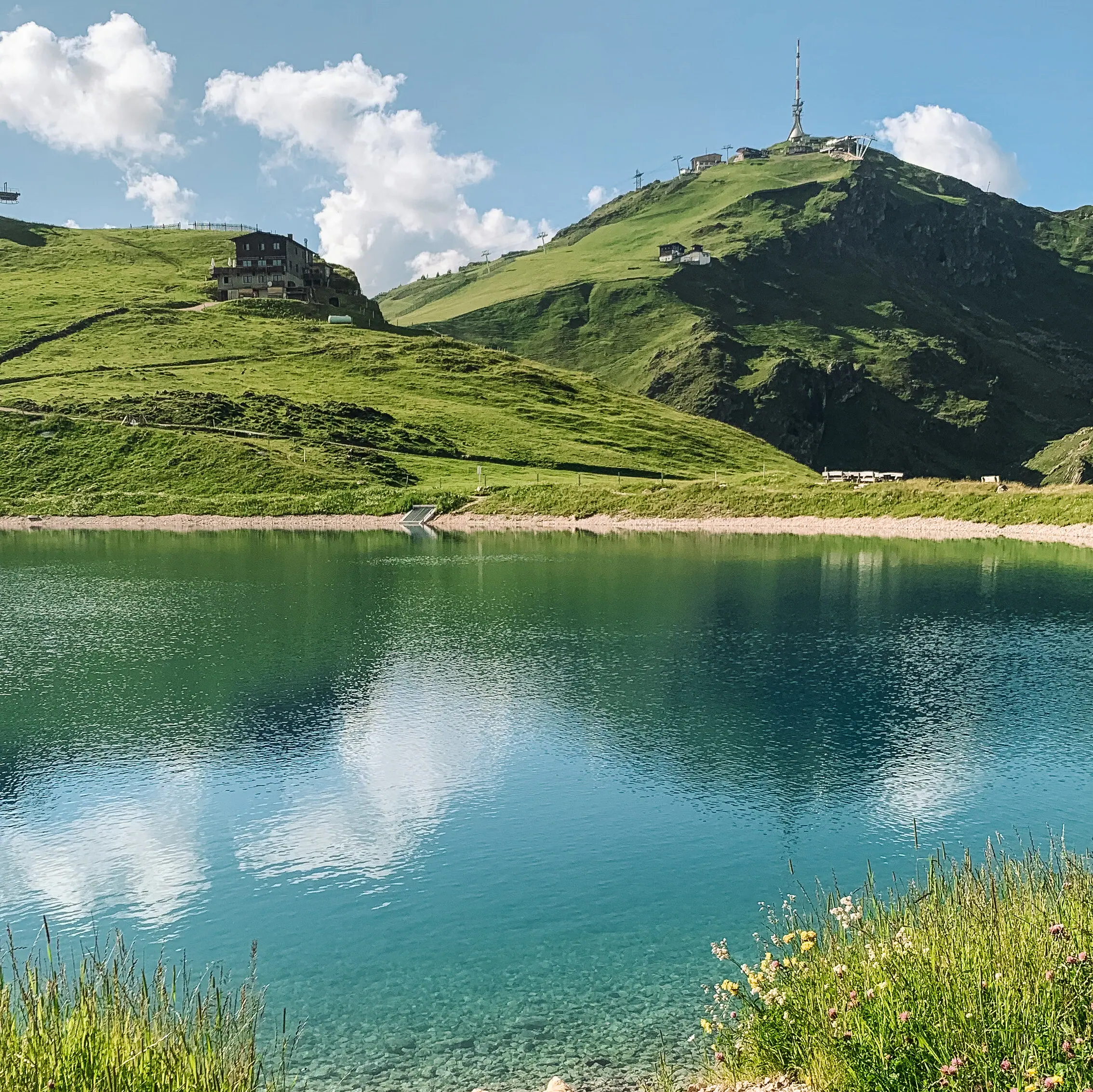 Hornköpflsee with a hill and a building in the background.