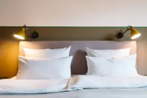 A bed with white pillows and a lamp at the HENRI Hotel Garmisch-Partenkirchen.