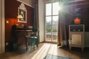 The Salon hotel room at the HENRI Hotel Kitzbühel with red walls, a desk and a window.