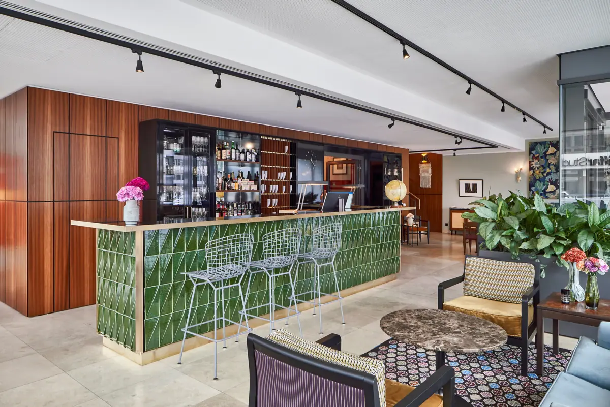 A bar with green tiles and chairs.