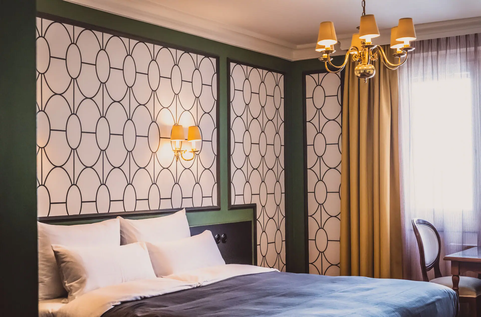 A bed with elegant bedding and a chandelier, framed by luxurious curtains.