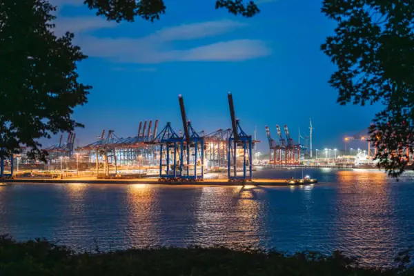 Large harbour with cranes and lights at night.