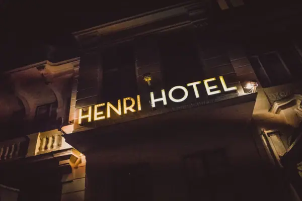 HENRI Hotel Berlin: façade, neon sign, night-time The bright, golden-yellow ‘HENRI HOTEL’ neon sign on the historic exterior façade of the hotel in Berlin at night.
