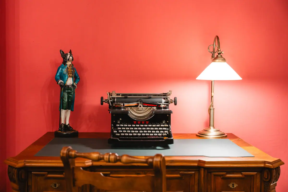 A desk with a lamp and a typewriter.