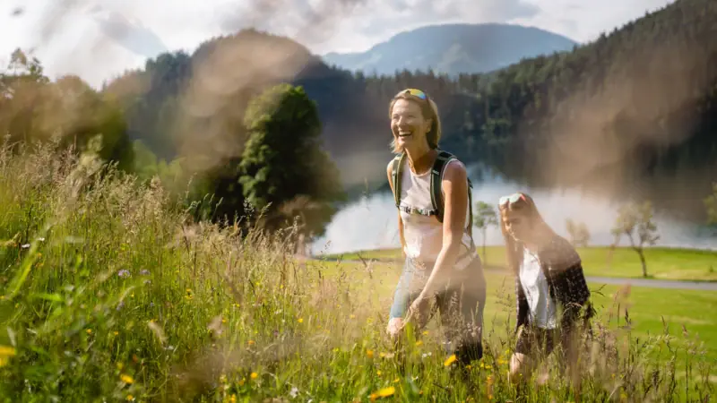 Two women in a field with grass and plants in the open air.