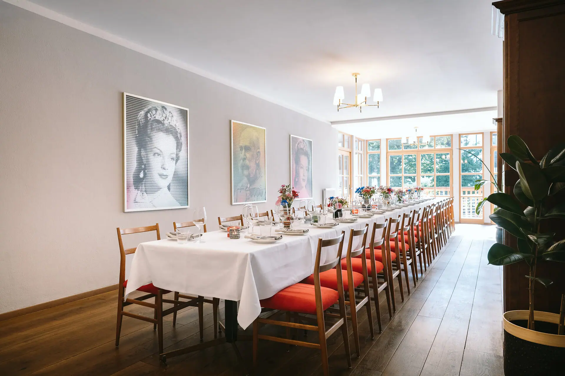 A long table with a white tablecloth and red chairs.