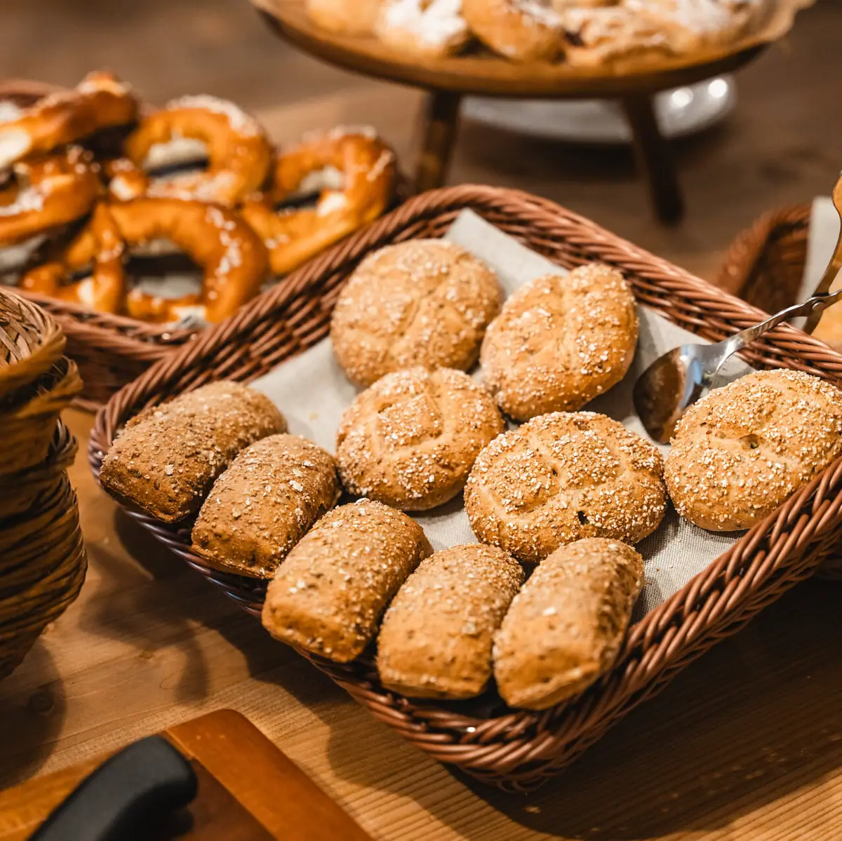 Several baskets of bread and pretzels on a breakfast buffet.